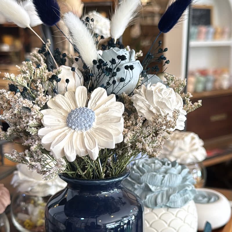 Marguerite en gypse au cœur bleu et lagurus dans un vase bleu nuit