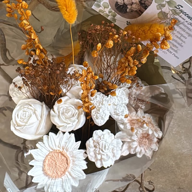 Bouquet de fleurs en gypse et lagurus orangé emballé dans du cellophane, avec la carte de la boutique