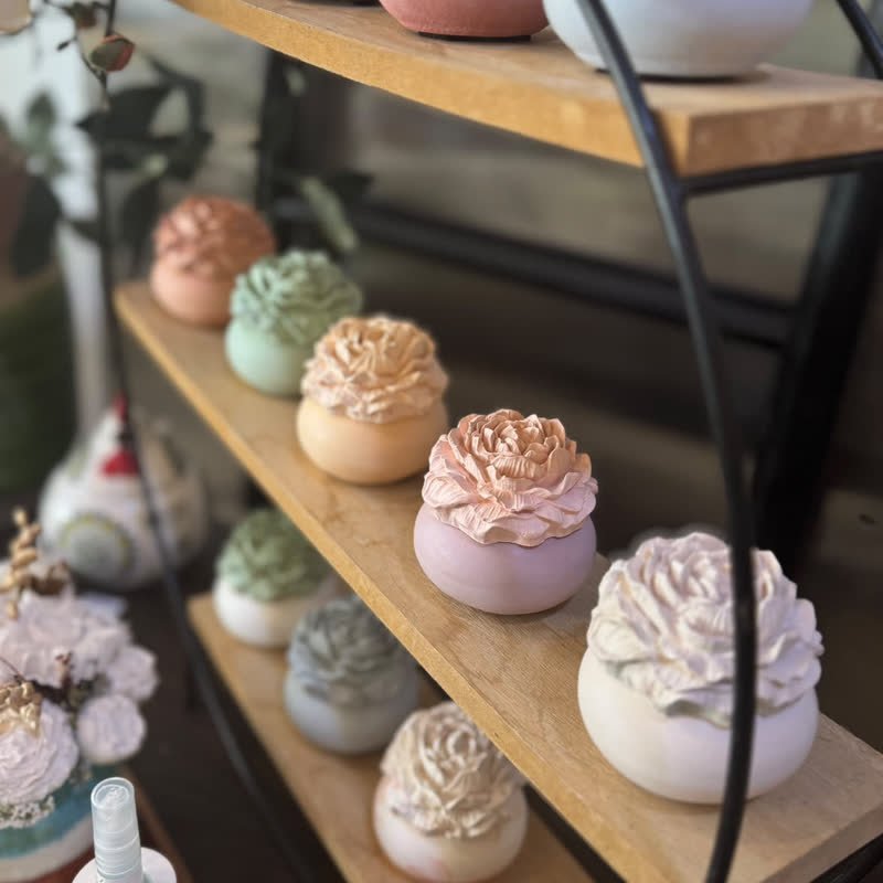 Pots à parfumer pastel dont le couvercle est une pivoine en gypse, alignés sur des étagères