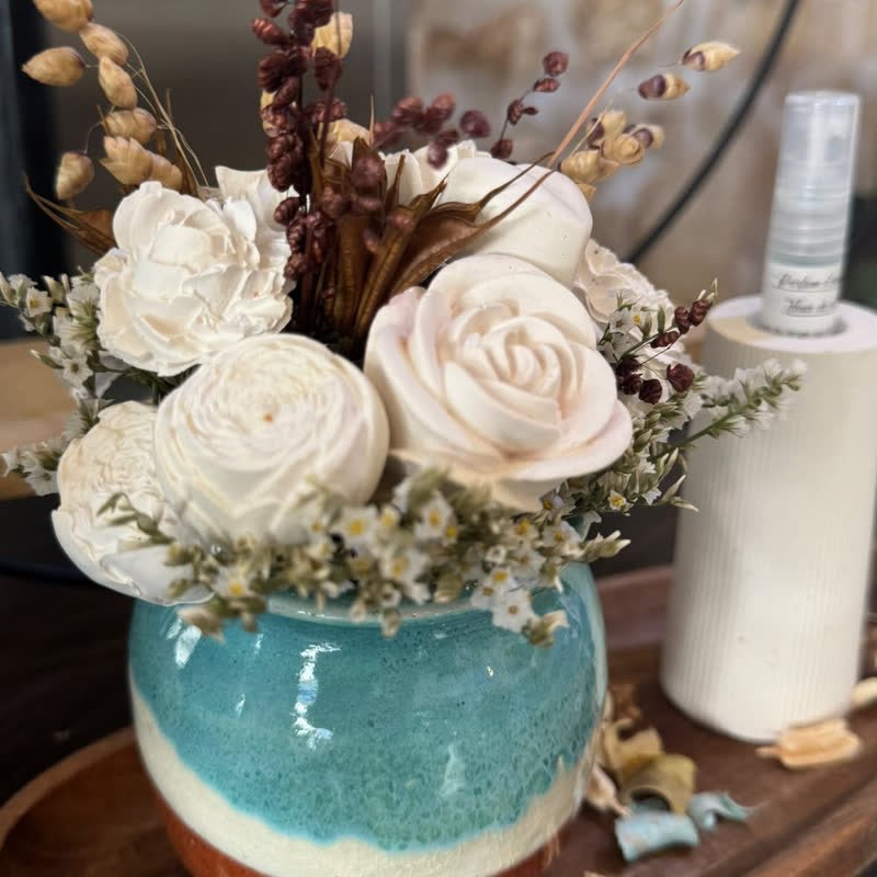 Roses blanches en gypse et graminées séchées dans un pot vernissé turquoise