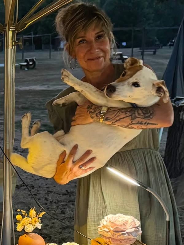 Alexandra Durand, fleuriste et gérante, avec son chien dans les bras derrière son stand de créations en gypse